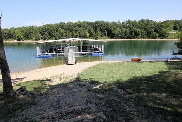 Dock on lake with beach and grassy area