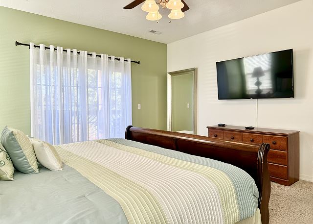 Primary king bedroom with television and balcony in Condo A-7