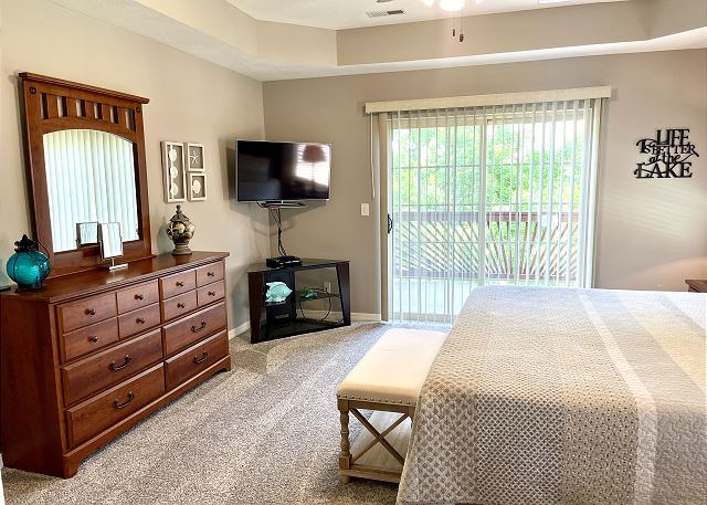 Primary bedroom with television and lake view in Condo A-9